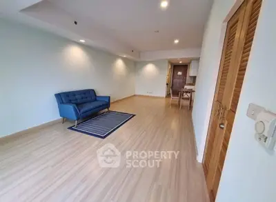 Spacious modern living room with sleek wooden flooring and stylish blue sofa.