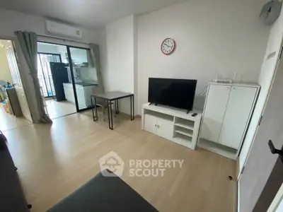 Modern living room with TV, air conditioning, and open kitchen layout in a cozy apartment.