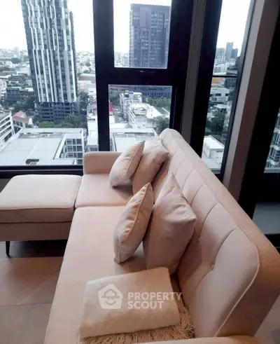 Modern living room with stylish sofa and panoramic city view from high-rise apartment window.