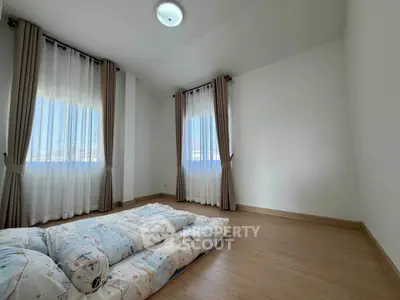 Spacious minimalist bedroom with natural light and wooden flooring