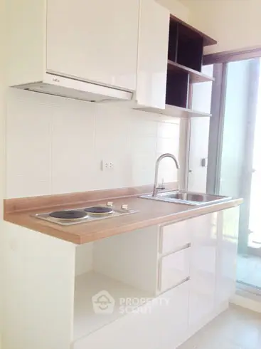Modern compact kitchen with sleek cabinetry and electric stove in bright apartment