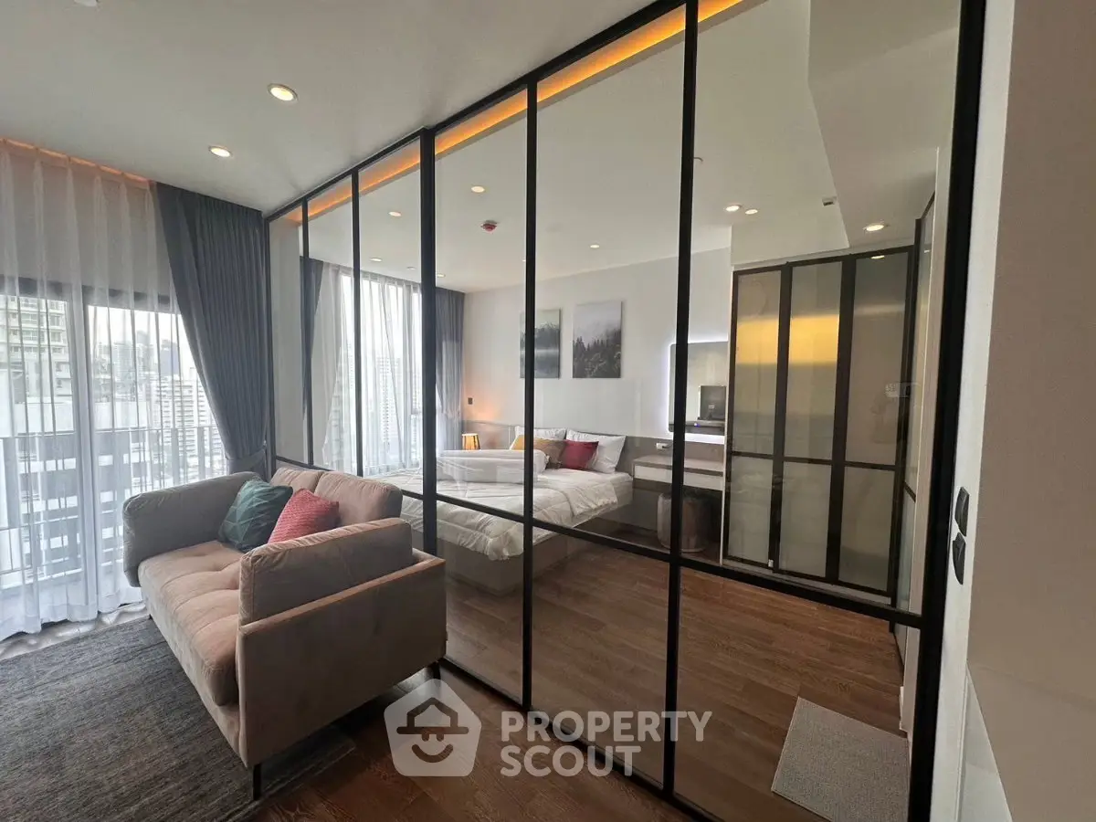 Modern apartment with glass partition, cozy living area, and stylish bedroom.