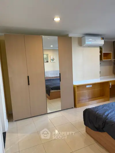 Modern bedroom with mirrored wardrobe and air conditioning unit
