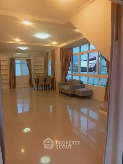 Spacious living room with large windows and elegant curtains, perfect for family gatherings.