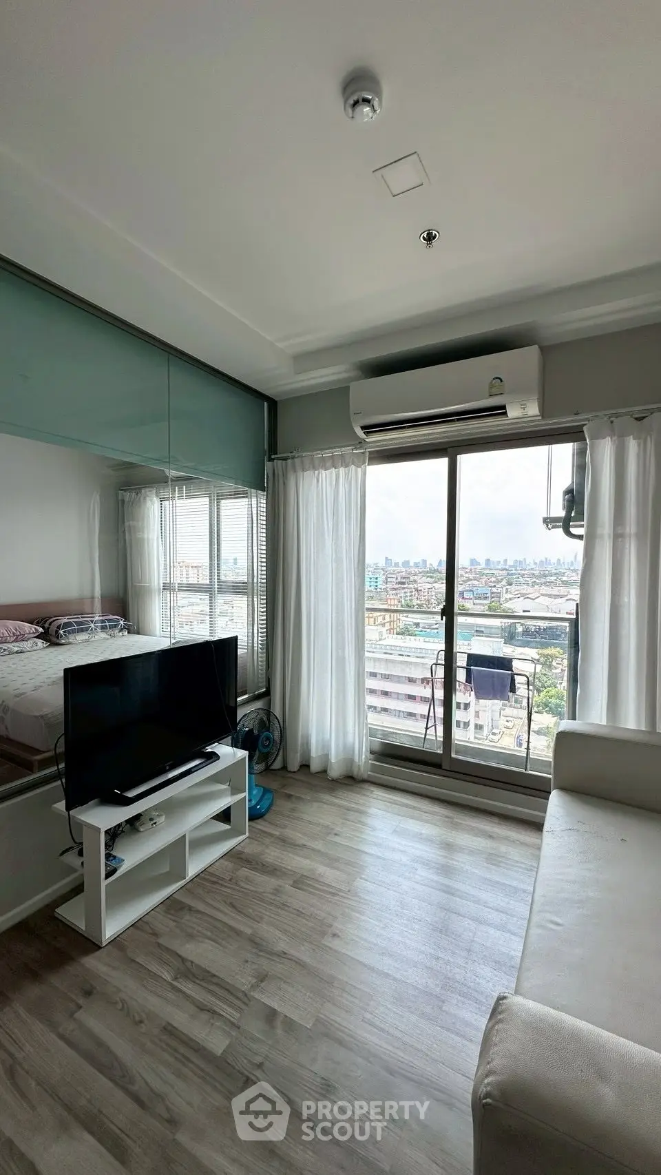 Modern living room with city view, featuring sleek flooring and large windows for natural light.