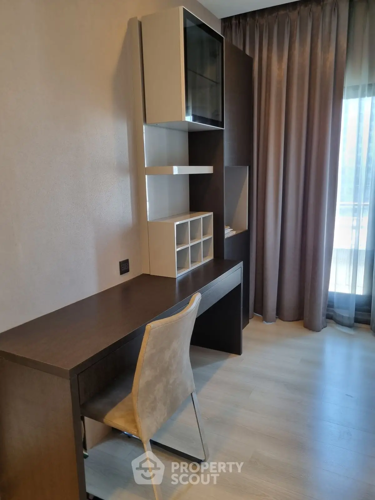 Modern study area with sleek desk and chair, featuring built-in shelving and natural light.