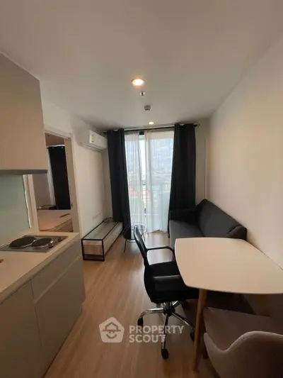 Modern compact living room with kitchenette and city view, ideal for urban living.