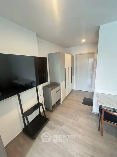 Modern apartment interior with sleek furniture and large TV, showcasing minimalist design and functionality.