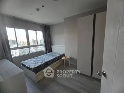 Modern bedroom with city view, featuring sleek furniture and large windows.