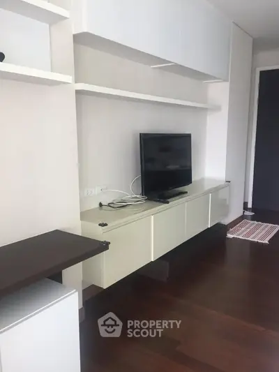 Modern living room with sleek TV stand and hardwood floors in a stylish apartment.