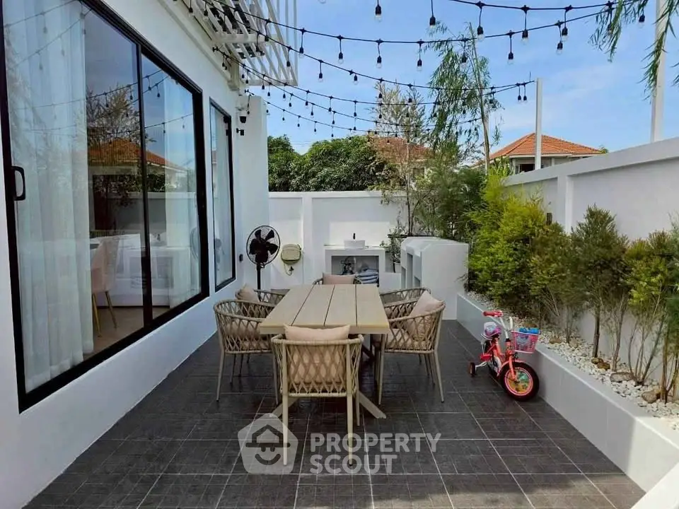 Charming outdoor patio with dining set and string lights, perfect for entertaining in a modern home.