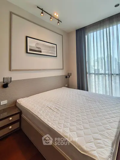 Modern bedroom with large window and city view, featuring elegant decor and ample natural light.