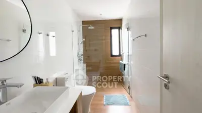 Modern bathroom with sleek fixtures and natural light, featuring a spacious shower and elegant design.