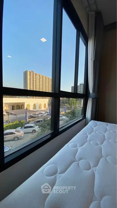 Spacious bedroom with large windows offering a stunning city view, perfect for urban living.