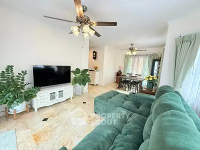 Spacious living room with elegant decor and green sofa, featuring a TV and dining area, perfect for family gatherings.