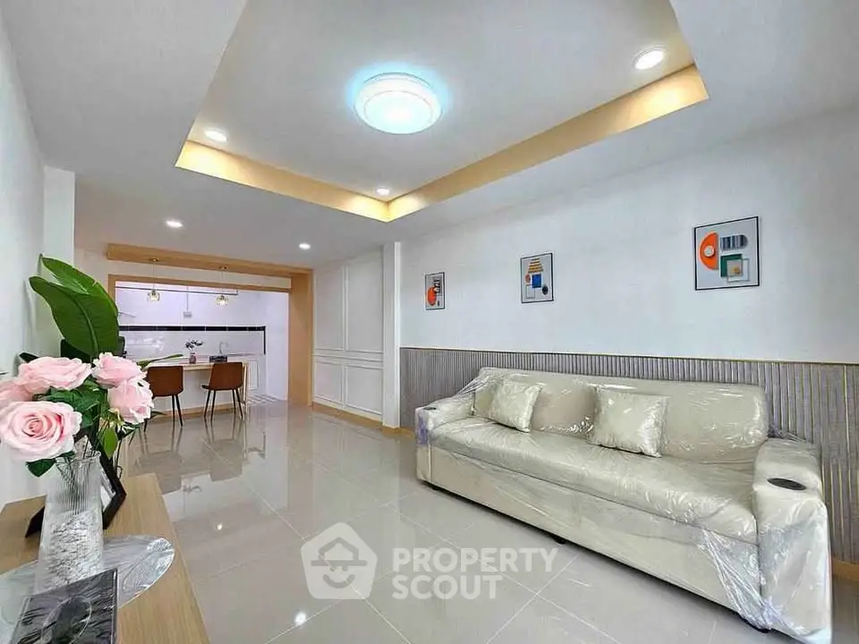 Modern living room with elegant decor and open kitchen layout, featuring sleek furniture and stylish lighting.