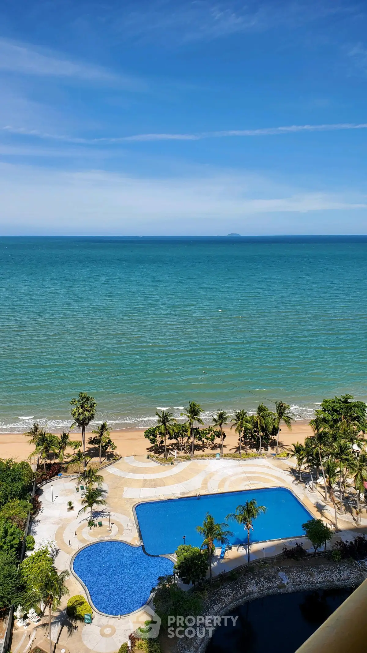 Stunning beachfront view with luxurious pool and palm trees, perfect for a tropical getaway.