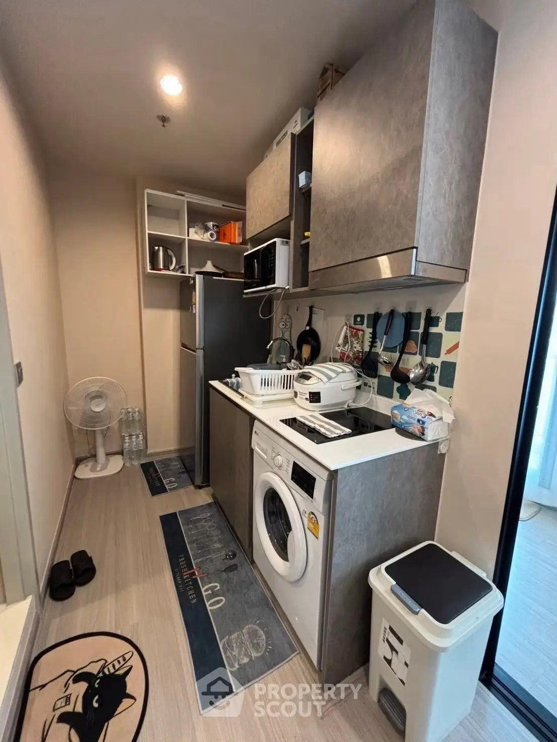 Compact kitchen with washing machine and modern appliances in cozy apartment.