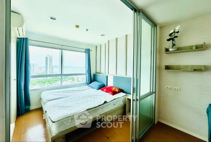 Bright bedroom with large window offering stunning city views, modern decor, and ample natural light.