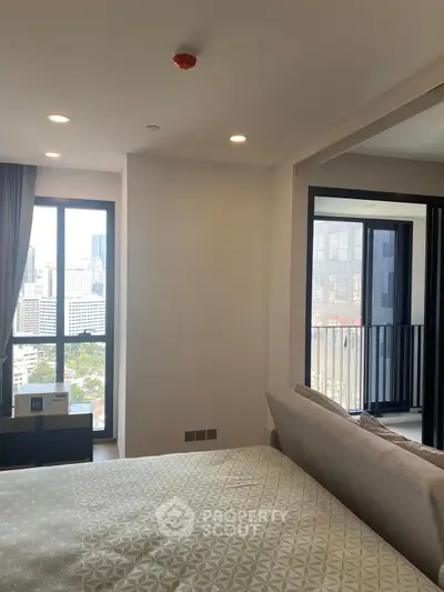 Modern bedroom with city view and balcony access in a high-rise apartment.