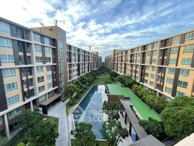 Stunning aerial view of modern apartment complex with central pool and lush greenery.
