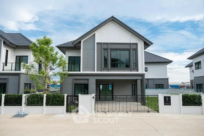 Modern two-story house with sleek design and spacious front yard in a serene neighborhood.
