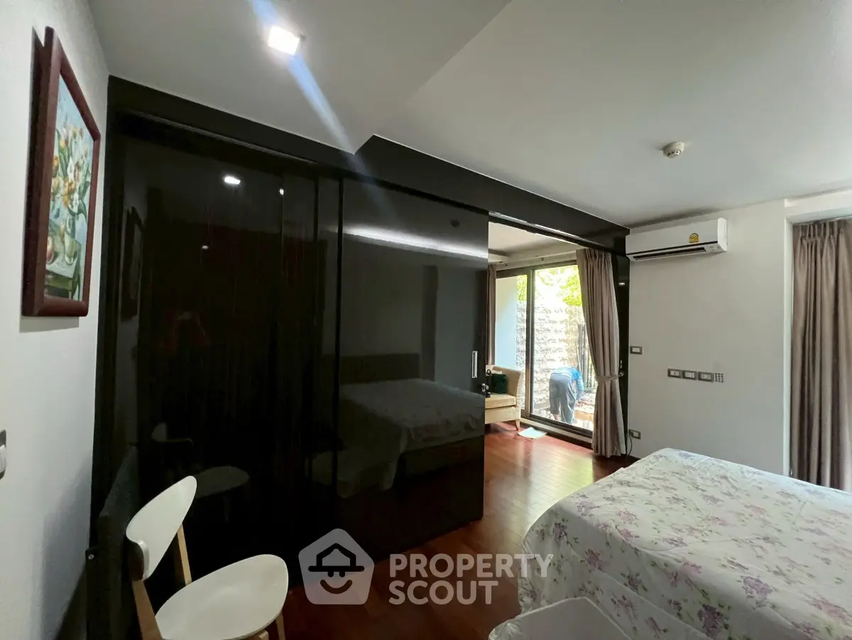Spacious bedroom with modern decor and large windows offering natural light and garden view.