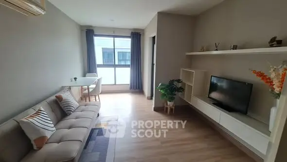 Modern living room with stylish decor and natural light, featuring a cozy sofa and sleek TV unit.