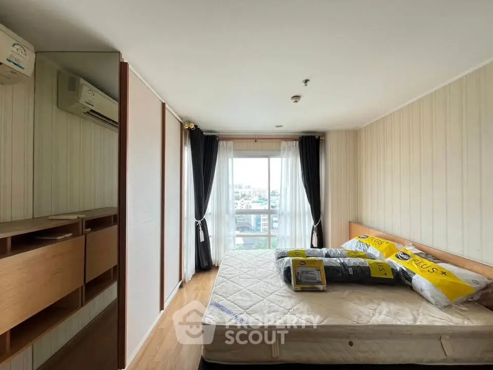 Cozy bedroom with large window and city view, featuring a comfortable bed and stylish wooden furniture.