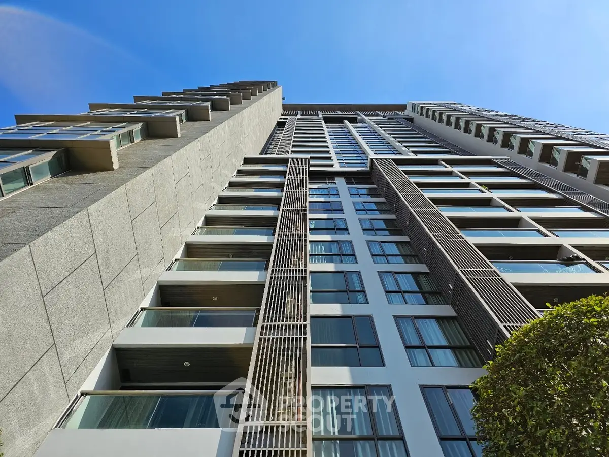 Modern high-rise building with sleek architectural design and large windows under clear blue sky.