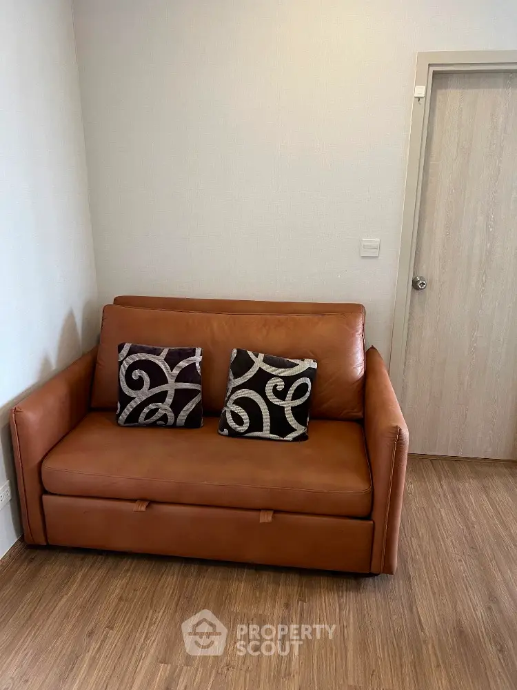 Cozy living room with stylish brown leather sofa and decorative pillows.