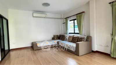 Spacious living room with modern sofa and air conditioning, featuring elegant wooden flooring and natural light.