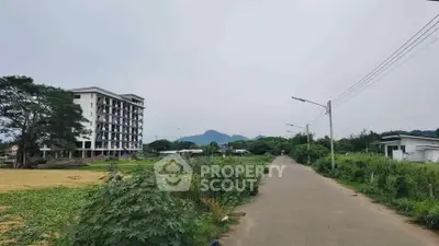 Scenic view of a residential building with lush greenery and mountain backdrop, ideal for tranquil living.