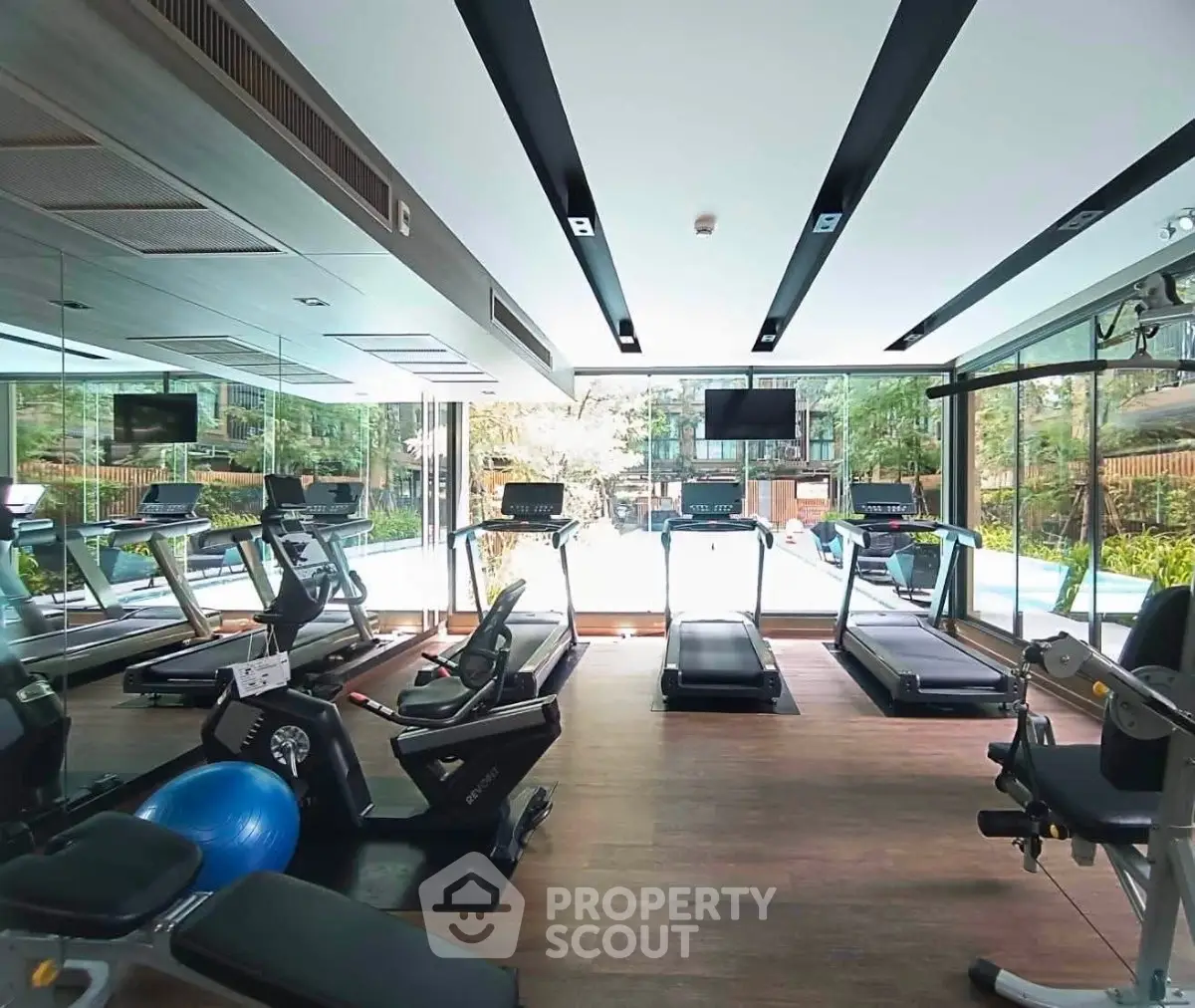Modern gym with state-of-the-art equipment and pool view in luxury residential complex.
