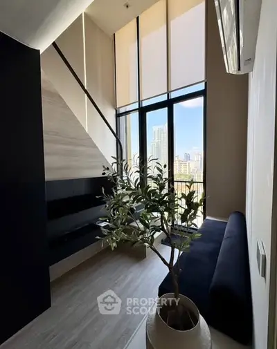 Modern loft apartment with high ceilings and city view, featuring stylish decor and large windows.