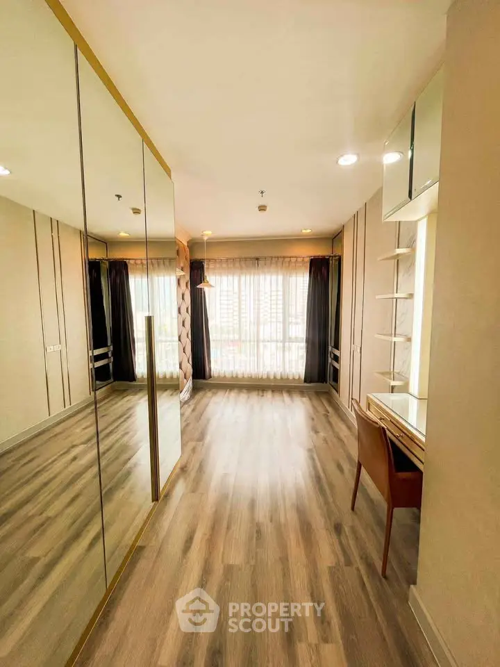 Spacious bedroom with elegant wood flooring and large mirrored closet doors.