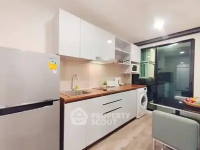 Modern kitchen with sleek cabinets, fridge, and washing machine in a stylish apartment.