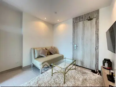 Cozy living room with modern decor, featuring a plush sofa, glass coffee table, and wall-mounted TV.