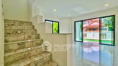 Spacious modern living room with marble staircase and large windows offering natural light.