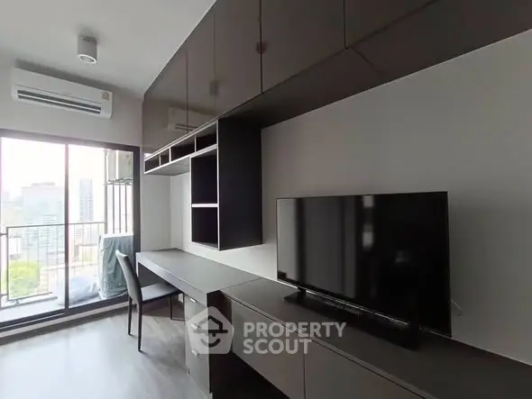Modern living room with sleek furniture and city view balcony in high-rise apartment.