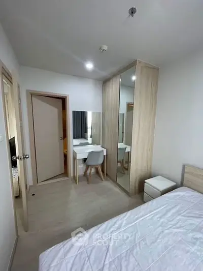 Modern bedroom with sleek wardrobe and cozy workspace in stylish apartment.