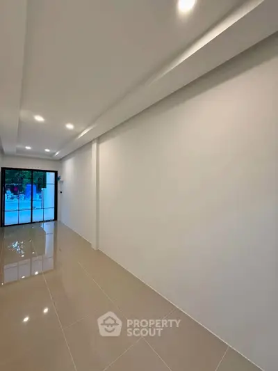 Spacious modern living room with glossy tiled floors and large glass doors.