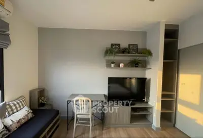 Modern living room with stylish decor and natural light, featuring a TV and cozy seating area.