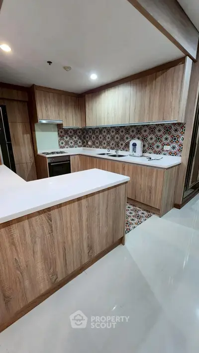 Modern kitchen with wood cabinetry and colorful backsplash, featuring sleek countertops and built-in appliances.