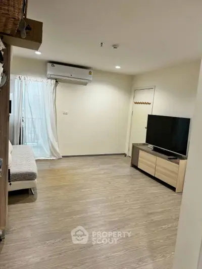 Modern living room with sleek wooden flooring and large TV setup