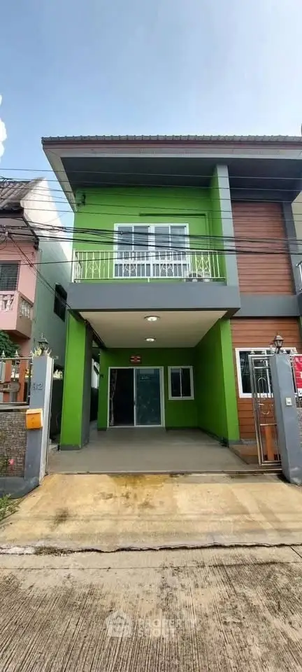 Modern two-story green townhouse with balcony and driveway