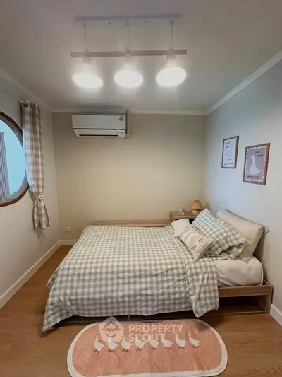 Cozy bedroom with stylish decor and natural light, featuring a comfortable bed and modern lighting.
