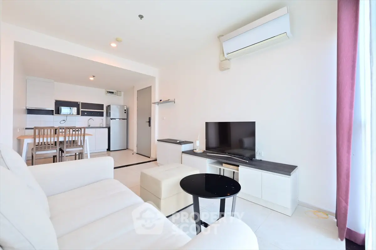 Modern open-plan living room with kitchen, featuring sleek furniture and air conditioning.