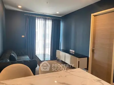 Modern living room with blue walls, elegant sofa, and natural light from large window.