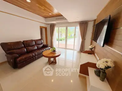 Spacious living room with leather sofa and large TV, featuring elegant decor and natural light.